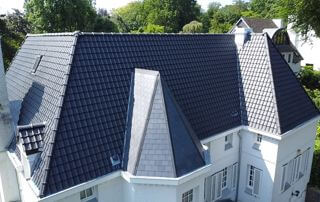 Maison avec toiture inclinée en tuiles noires réalisée par Belgo-Renov